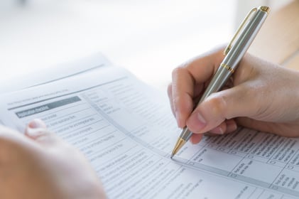 hand-with-pen-over-application-form