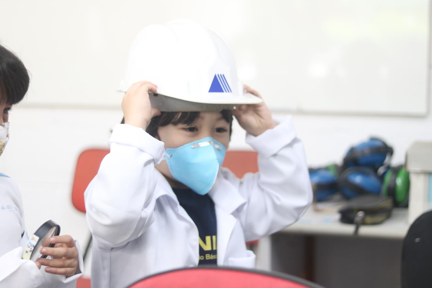 Criança brincando com chapéu de obra