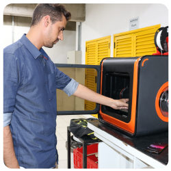 Homem do curso de Engenharia Mecatrônica do eniac fabricando algo na impressora 3D